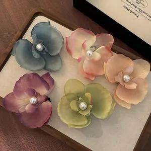Détail de cinq pinces à cheveux orchidées colorées avec perles sur un plateau en bois