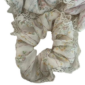 Chouchou en dentelle à fleurs avec motifs jaunes et violets sur fond de tissu beige