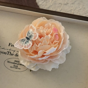 Blue-tinted camellia hair clip with silk fabric petals and a delicate embroidered butterfly