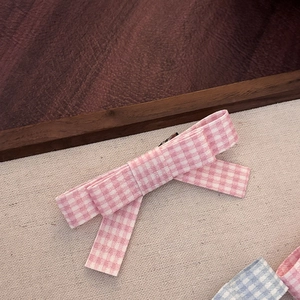 Pink checkered bow hair clips in Korean style on a minimalist fabric background