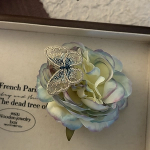Close-up of intricate blue embroidered butterfly hair clip on a purple flower