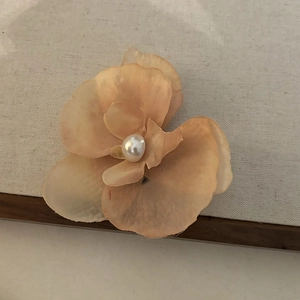 Détail de la pince à cheveux orchidée orange clair avec pétales dégradés et perle blanche