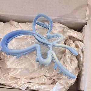 Détail de la pince à cheveux papillon bleu clair montrant le ressort et le fini mat