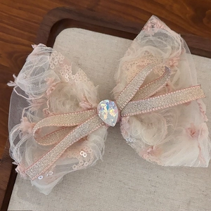 Pink lace bow hair clip with shimmering mesh fabric and a teardrop rhinestone center