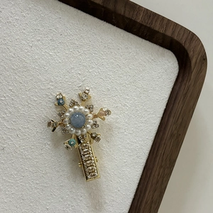 Detailed close-up of a floral pearl hair clip with blue beads and crystals on gold plating