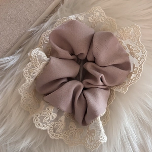 Détail d'un chouchou en maille rose avec broderie élégante en dentelle blanche fleurie