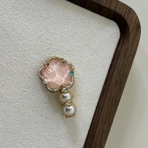 Close-up of pink flower petal hair clip with pearls and sparkling blue gemstone detail