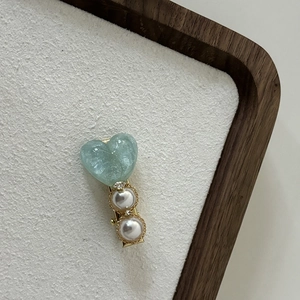 Detail of elegant hair clip with a pale green heart and pearls on a gold metal base