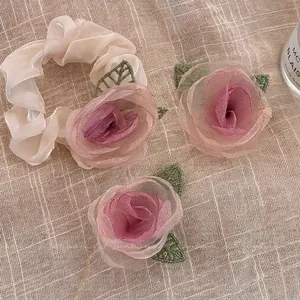 Florales Haargummi-Set mit Organza-Rose und grünen Blättern auf Leinenhintergrund