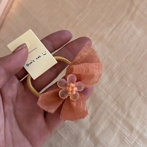Détail d'une barrette à cheveux avec nœud orange et fleur rose pour petites filles