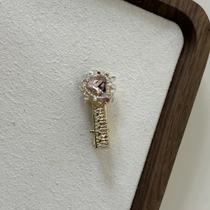 Detailed macro view of heart-shaped pink crystal hair clip with pearls and golden alloy base