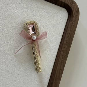 Detail of pink crystal and sheer ribbon flower hair clip on a wooden display tray