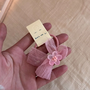 Détail de la pince à cheveux avec nœud en soie rose et centre fleuri sur carte