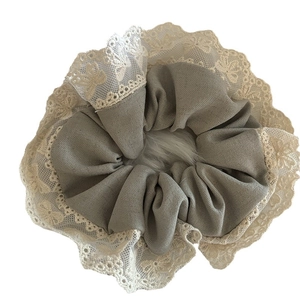 Chouchou en dentelle vert grisâtre avec bordure crochetée et pompon en fausse fourrure
