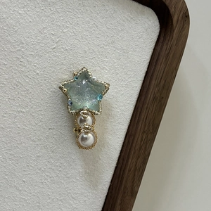 Detail of light blue star hair clip with pearls on a textured white background