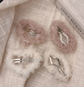 Détails de quatre barrettes en tulle plissé rose et beige sur tissu en lin