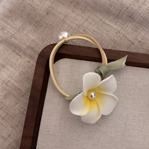 Detailed shot of an elastic hair tie with white floral decor, yellow center and pearl accent