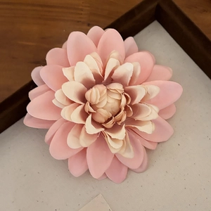 Dettaglio di una grande clip per capelli a forma di dalia in tessuto rosa e beige