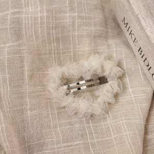 Barrette BB élégante en dentelle blanc cassé sur un fond en lin naturel rustique