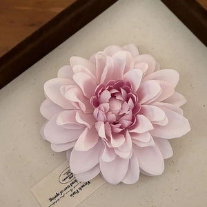 Dettaglio macro della grande molletta per capelli a fiore rosa tenue su vassoio retrò