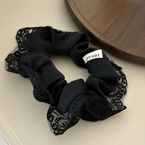 Elegant black satin scrunchie with delicate lace edges for a French romantic style