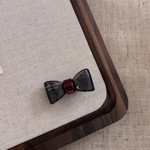 Eleganter transparenter Acetat-Haarclip als Schleife mit Goldlogo in Rot und Schwarz