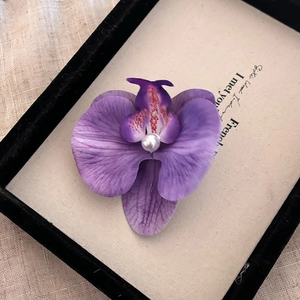 Vue détaillée de la pince à cheveux orchidée violette avec pétales dégradés et perle