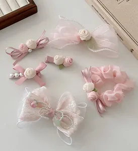 Vue détaillée de pinces à fleurs en tissu rose et de chouchous en organza avec perles