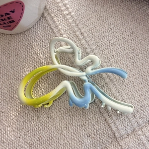 Détail de la pince à cheveux papillon avec dégradé jaune blanc bleu et ressort métallique