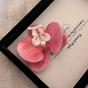 Gros plan sur la pince à cheveux orchidée rose avec perle sur fond décoratif vintage