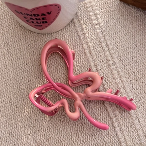 Détail de la pince à cheveux papillon dégradé rose sur fond de tissu tissé beige