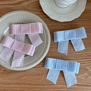 Close-up of pink and blue plaid hair clips with white scalloped lace edges on a plate