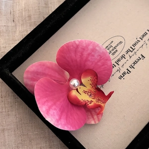 Détail de la pince à cheveux orchidée rose avec pétales réalistes et perle centrale
