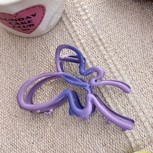 Détail d'une pince à cheveux papillon violet mat sur un tissu beige tissé