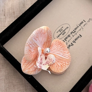 Pince à cheveux orchidée pêche élégante avec perle dans une boîte minimaliste