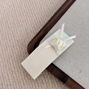 Détail d'une pince à cheveux en tissu crème avec rose en satin sur plateau en bois
