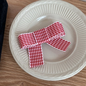 French style red and white plaid bow hair clip on a decorative ceramic plate