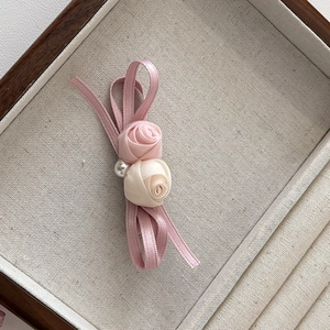 Détail d'une pince à cheveux rose en satin faite main avec fleurs en soie et perle