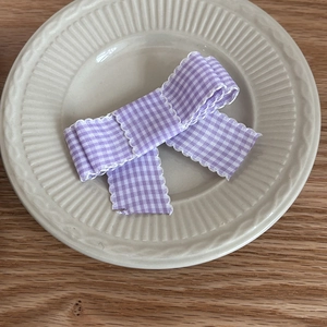 Sweet purple and white plaid bow hair clip on a vintage ceramic plate on wooden table