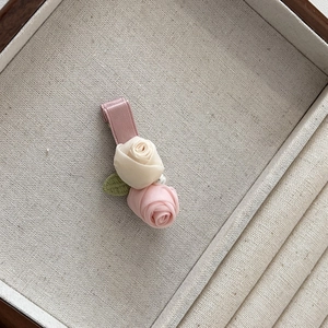 Détail d'une pince à cheveux rose en tissu fait main avec ruban de soie et perle factice