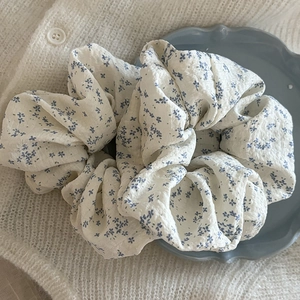 Chouchou fleuri à motifs bleus sur tissu texturé blanc dans une assiette décorative
