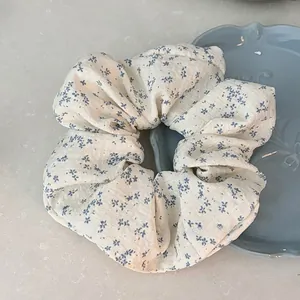 Gros plan d'un chouchou à fleurs bleues sur une assiette montrant la texture du tissu