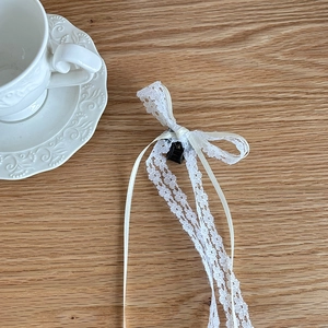 Sweet white lace bow hair clip with streamers on a rustic wooden background