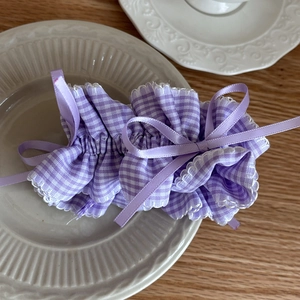 Close-up of purple gingham scrunchie with a ribbon bow on a decorative ceramic plate