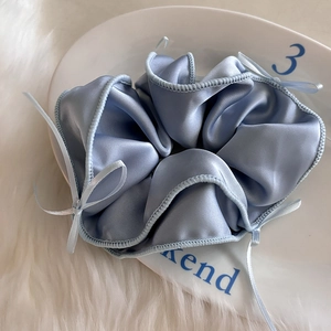 Chouchou en satin bleu clair avec ruban sur un plateau décoratif en céramique