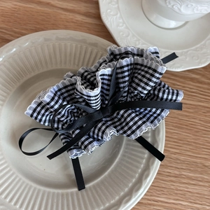 Detail of checkered hair scrunchie with satin bow on a ceramic plate