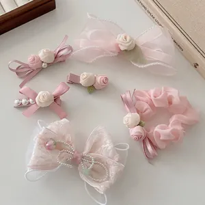 Barrettes à nœuds en dentelle rose et chouchou rose sur un fond élégant