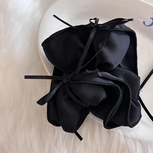 Chouchou élégant en satin noir avec nœud et longs rubans sur fausse fourrure blanche
