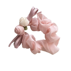 Chouchou en mousseline rose avec roses en tissu et rubans sur un fond blanc
