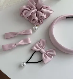 Détail d'accessoires en satin rose avec pinces à nœud, chouchou perle et serre-tête